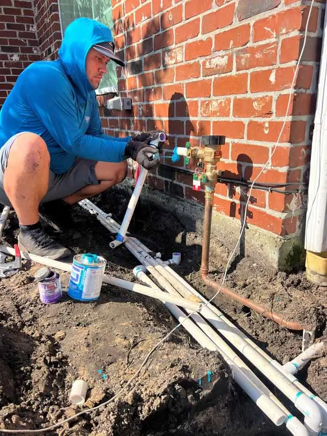 Sprinkler system pipe repair beside home foundation