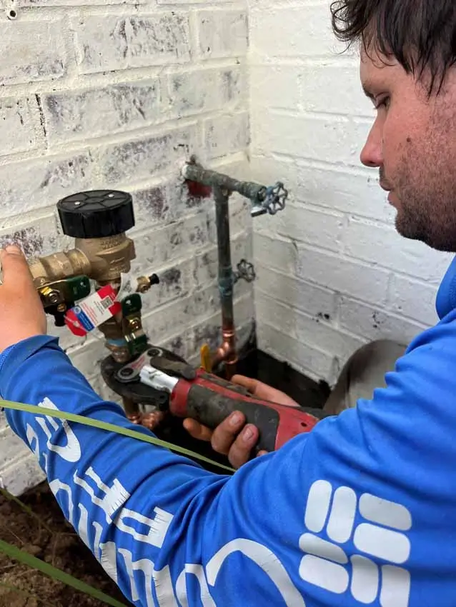Irrigation technician repairing backflow preventer connection